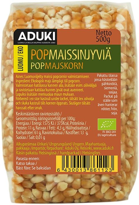 Aduki Luomu Popcorn Maissinjyvät; 500 g:n muovipussi luomupopcorn-maissinjyviä, suorakulmainen pyöristetyin yläkulmin; pakkaus on läpinäkyvä, näyttäen selvästi keltaiset maissinjyvät sisällä; mattapintaisessa etiketissä mustaa ja vihreää suomen- ja ruotsinkielistä tekstiä sekä ravintosisältötiedot; ei ihmisiä tai käsiä näkyvissä; neutraali tausta, tuote kuvattu suoraan edestä.