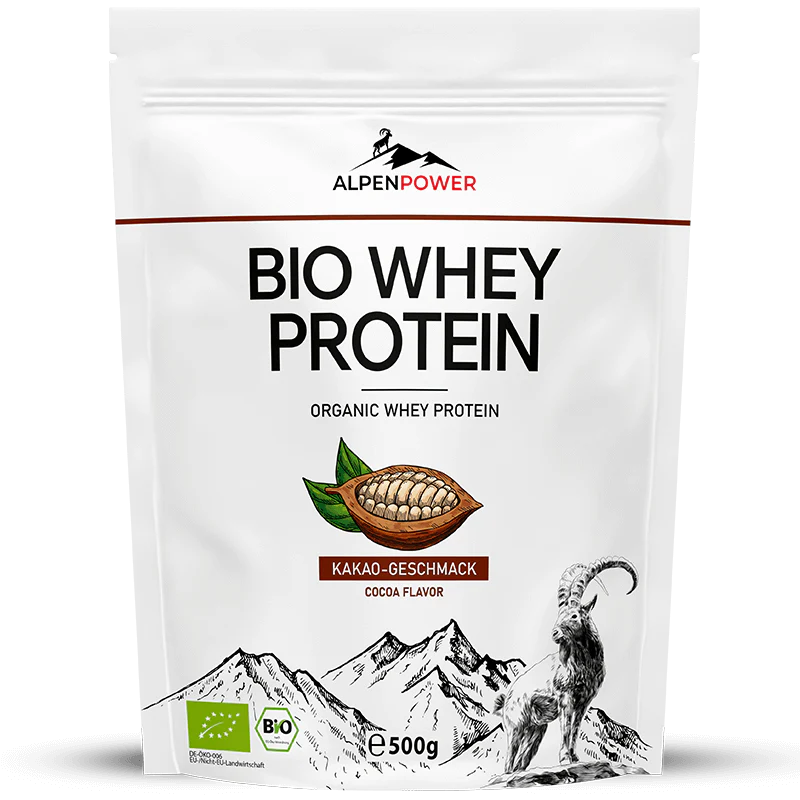 AlpenPower Luomu Heraproteiini Suklaa; valkoinen AlpenPower BIO Whey Protein -pussi mattapinnalla; kuvituksena painettu kaakaopalko, tyylitellyt vuoret ja vuohi; muoto suorakulmainen uudelleensuljettavalla yläreunalla; etiketissä lihavoitua groteskitekstiä, joka kertoo luomuheraproteiinista ja runsaasta kaakaomausta, 500 gramman koko; pelkistetty studiotausta, ei ihmisiä näkyvissä.