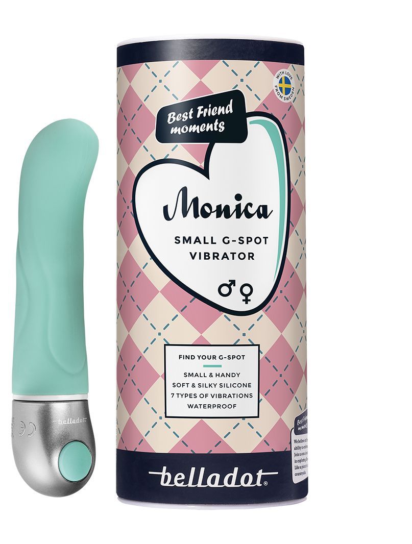 Belladot Monica Small G-piste Vibraattori: turkoosi vibraattori esillä sylinterimäisen pakkauksensa vieressä sydänkuvituksin ja tuotetiedoin; vibraattorin pinta on sileä ja mattaa, muoto kaareva kapenevalla kärjellä; pakkaus on pystyasennossa groteskikirjasimella ja ääriviivakuvitetuin sydämin; tausta on valkoinen, ei ihmisiä tai käsiä näkyvissä, tavanomainen edestäpäin otettu tuotekuva.