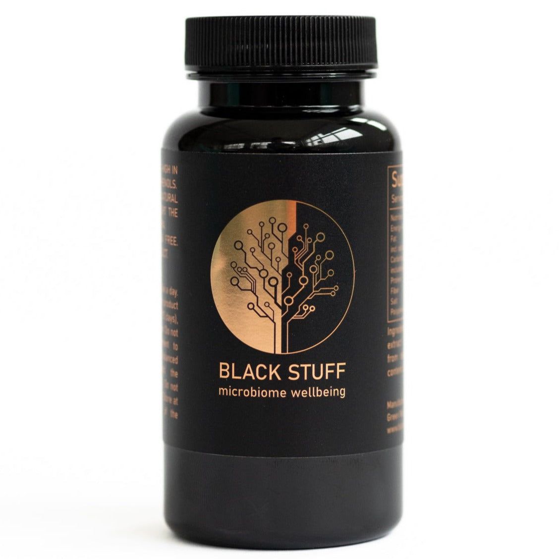 Black Stuff Havupuu-uute kapselit; musta sylinterinmuotoinen pullo mattapintaisena; etiketissä teksti "BLACK STUFF microbiome wellbeing" lihavoidulla groteskikirjasimella; kultainen pyöreä logo tyylitellyllä puukuvalla; pieniä käyttöohjeita painettu pääetiketin molemmin puolin; kuvassa pelkkä pullo neutraalilla taustalla, ei käsiä tai ihmisiä.