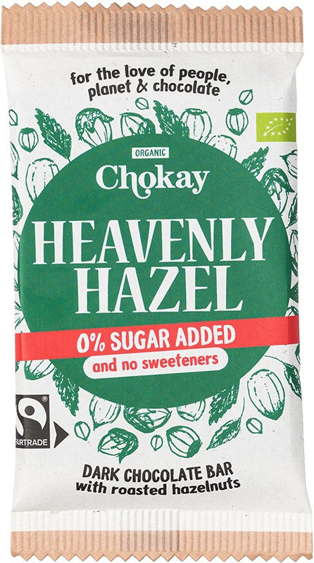 Chokay Heavenly Hazel -tumman suklaan kääre, merkitty 0 % lisättyä sokeria ja luomu, kuvituksena paahdettuja hasselpähkinöitä. Valkoinen ja vihreä mattapakkaus näyttää käsinpiirrettyjä hasselpähkinäkuvituksia. Tuotenimi on lihavoidulla antiikva- ja pääteviivattomalla fontilla. Ihmisiä tai käsiä ei näy. Kuva on lähikuva pelkistetyllä taustalla.
