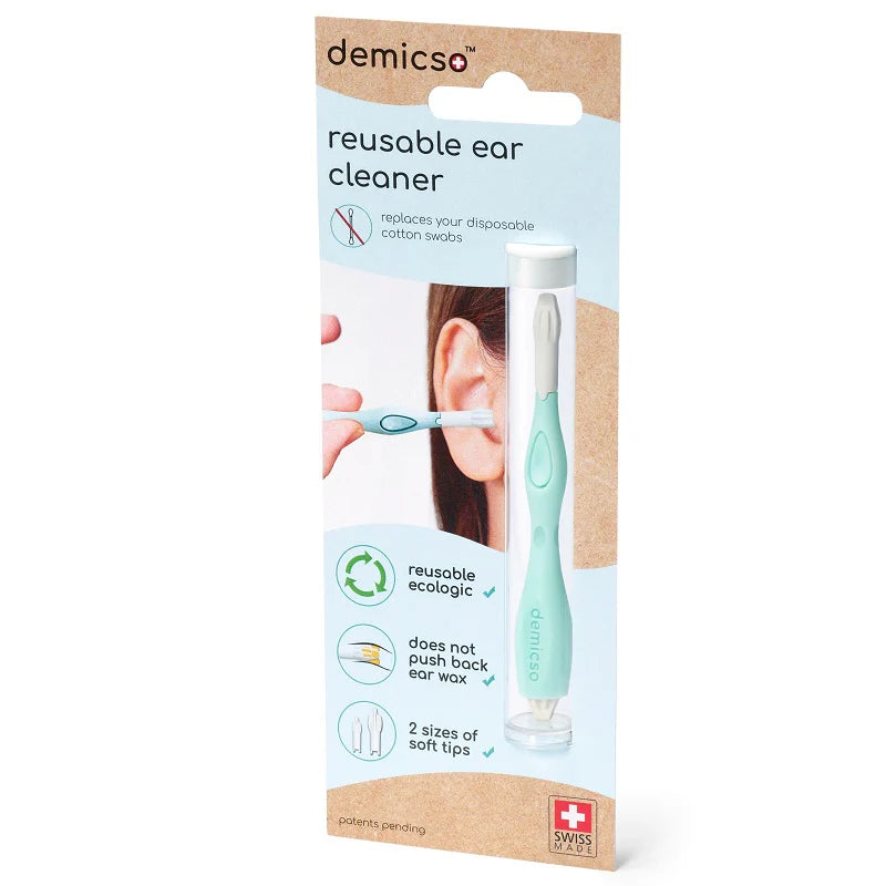 Packaging for a demicso reusable ear cleaner, featuring the product and clear illustrations. Claims include being reusable, eco-friendly, not pushing back ear wax, and offering two sizes of soft tips. The Swiss cross logo is displayed at the bottom. White rectangular packaging with product photo shows a slim tool with two silicon tips; blue and green color accents are present. Matte finish box displays sans-serif font; plain white background; no people or hands visible.