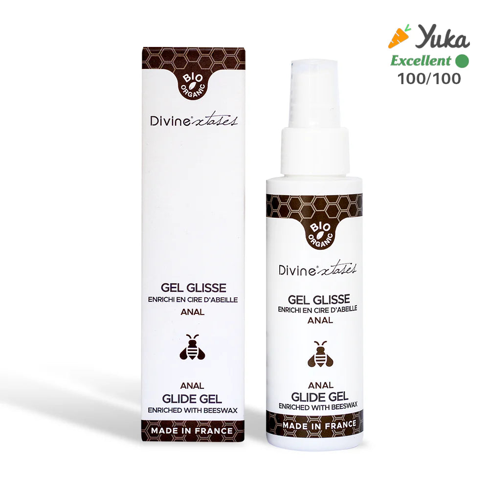 DivineXtases Anaaliliukuvoide; pullo ja rasia Divine Gel Glisse Anal Glide Gel -liukuvoidetta mehiläisvahalla, merkitty Made in France; molemmat valkoisia mattapinnalla, koristeltu hunajakennokuvioin ja yksityiskohtaisella keltamustalla mehiläiskuvituksella; Yuka Excellent -pistemäärä 100/100 näkyy selkeästi oikeassa yläkulmassa; tuotenimi lihavoidulla groteskikirjasimella; ei ihmisiä tai käsiä, valkoinen tausta, suora edestä otettu kuva.