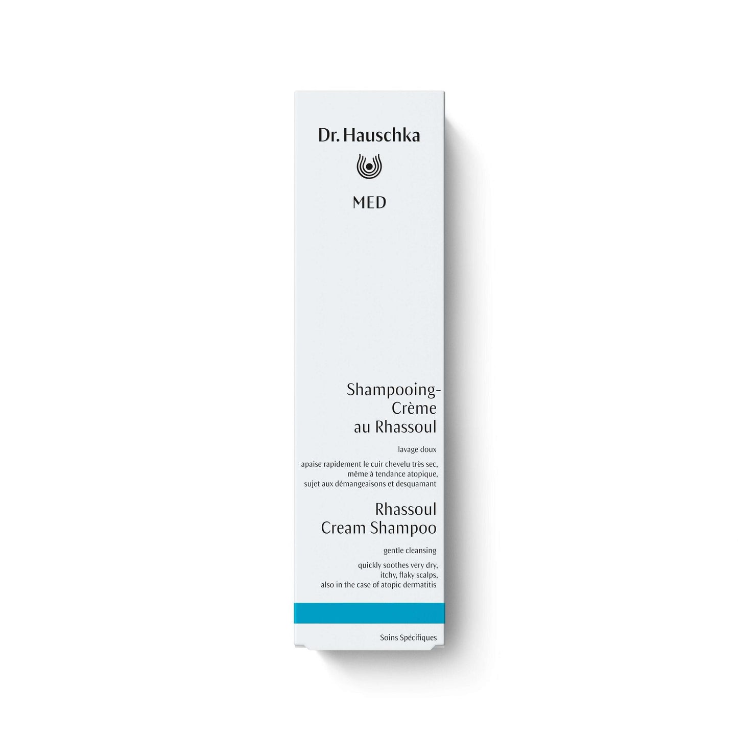 Dr.Hauschka Med Rhassoul-savishampoo; valkoinen, suorakulmainen pakkaus mustalla ja sinisellä ranskan- ja englanninkielisellä tekstillä; yksinkertainen pyöreä logo pakkauksen yläosassa.