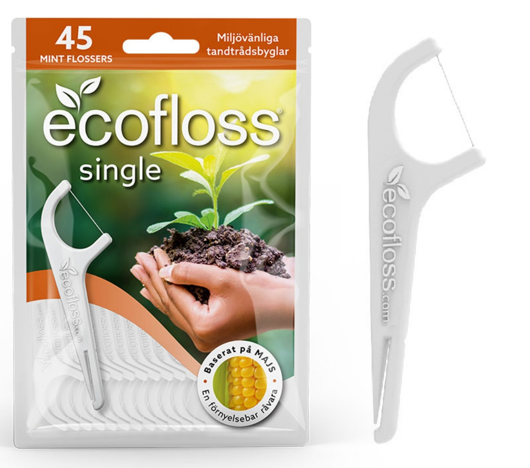 Ecofloss Single Hammaslankain; pakkaus, jossa 45 ecofloss single -minttuhammaslankainta, kuvassa kädet pitelemässä maata ja tainta, korostaa ympäristöystävällisiä, maissipohjaisia materiaaleja; pakkaus on pääosin valkoinen ja vihreä mattapinnalla, teksti selkeällä groteskifontilla; yksi biohajoava hammaslankain luonnonvalkoista muovia kaareutuvalla kahvalla ja kaksois-piikeillä on esillä erikseen oikealla yksivärista taustaa vasten.