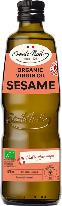 Emile Noël Luomu Seesamöljy, 500 ml pullo vihreällä korkilla, ruskea lasi ja beige-oranssi etiketti, jossa reilun kaupan ja luomusertifikaatit; pullo sylinterimäinen, korkki sileä muovia; brändinimi antiikvafontilla, muu teksti groteskifontilla; keskeiset sertifikaatit kuvakemuodossa etiketin alaosassa; tausta valkoinen, ei rekvisiittaa eikä ihmisiä, studiokuva silmän korkeudelta.