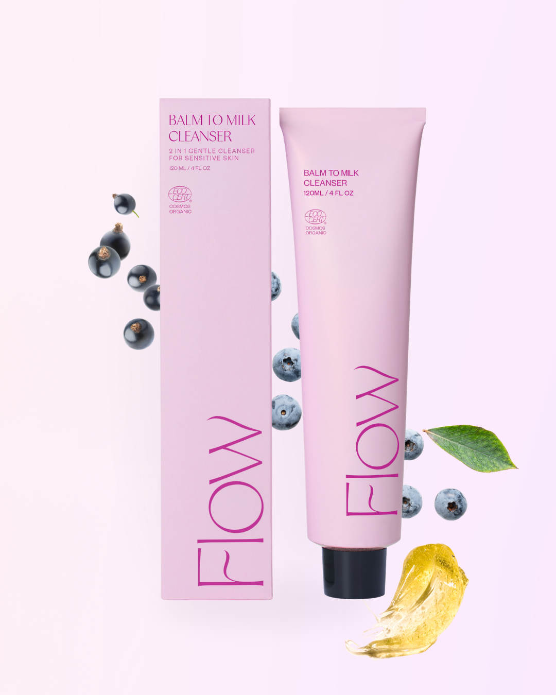 FLOW Cosmetics Balm to Milk Puhdistusvoide: pinkki tuubi ja yhteensopiva rasia tekstillä "Flow Balm to Milk Cleanser" seisovat pystyssä mustaherukoiden, mustikoiden, vihreän lehden ja keltaisen balsamiraidan ympäröiminä vaaleanpinkillä pohjalla; pakkaus on mattapintainen, tuubi pehmeää muovia ja rasia suorakulmainen kartonkia; yksinkertainen valkoinen teksti tuotemerkinnässä; ei ihmisiä tai käsiä näkyvissä, kuva on ylhäältä otettu asetelma.