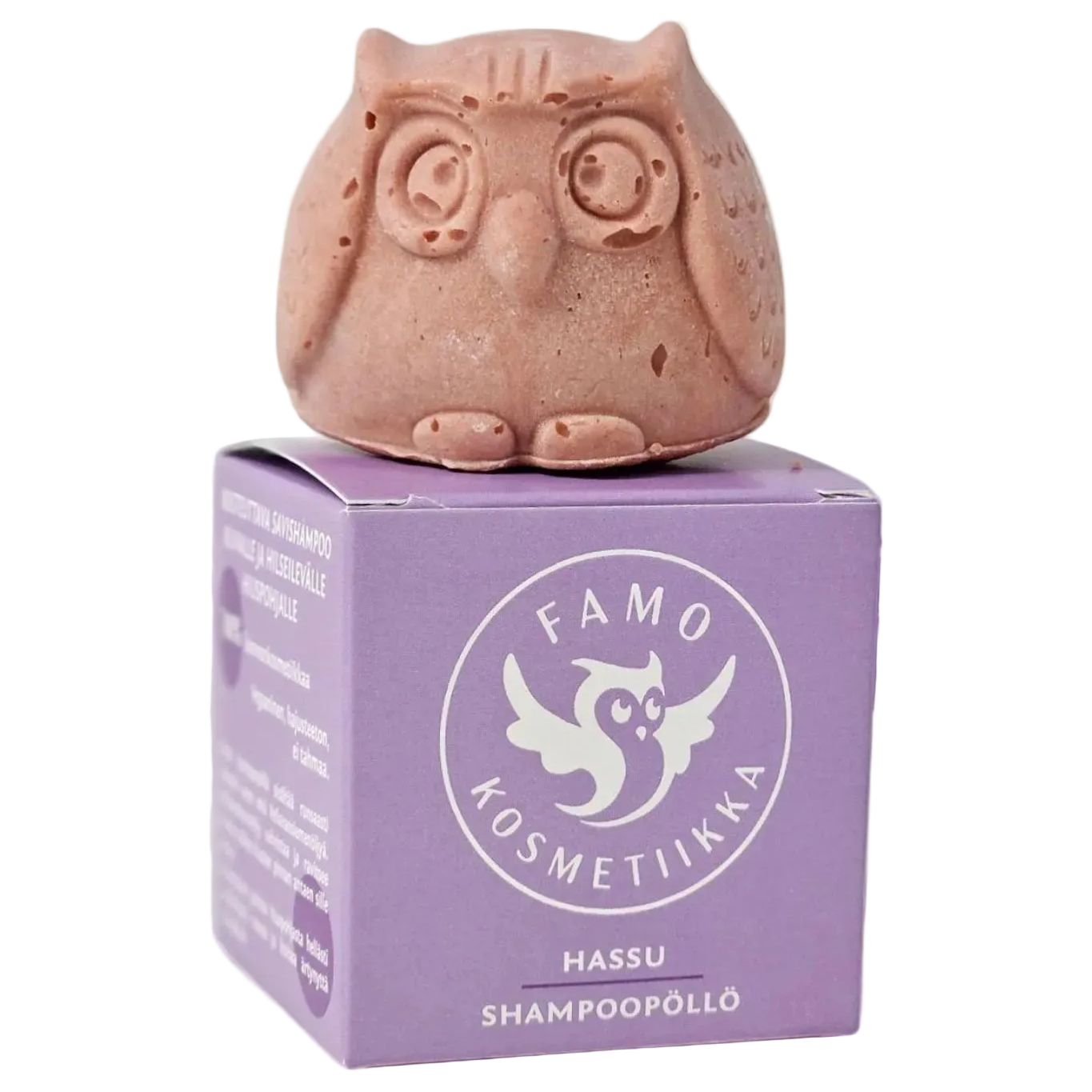 Famo Hassu Shampoopöllö: pinkki, mattapintainen pöllönmuotoinen kiinteä shampoopalanen suorakulmaisen violetin kartonkirasian päällä; rasiassa Famo Kosmetiikka -tuotenimi, teksti "Hassu Shampoopöllö" sekä tyylitelty valkoinen pöllölogo ja lisää tuotetietoa vaihtelevan painoisella groteskikirjasimella; ei rekvisiittaa näkyvissä.