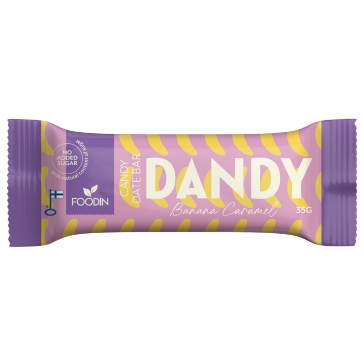 Foodin Dandy Candy Date Bar Banana Caramel; suorakulmainen, mattapintainen patukka on käärittynä violettiin ja keltaiseen pakkaukseen; kääreessä lukee lihavalla valkoisella ja keltaisella typografialla DANDY Banana Caramel, Candy Date Bar sekä No added sugar; 35 gramman patukan valmistaja on FOODIN; kuvassa ei näy ihmisiä tai käsiä, tausta on yksivärinen.