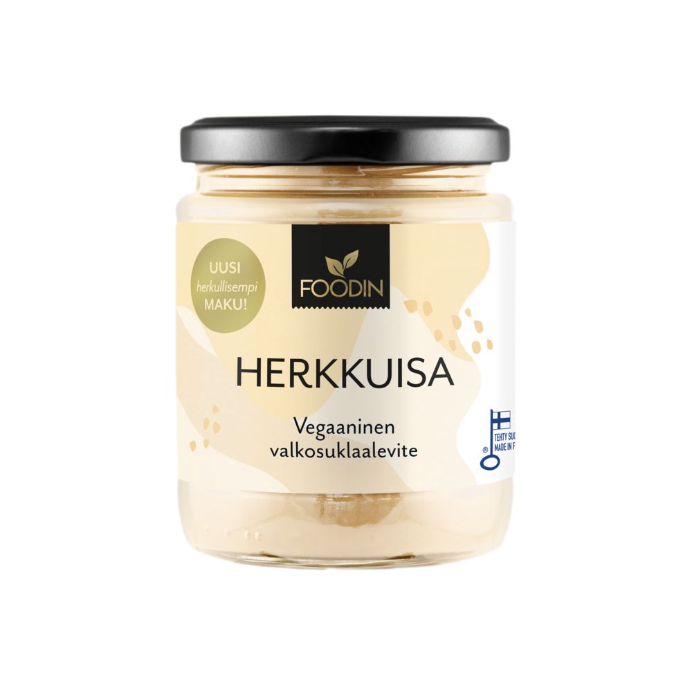 A glass jar of Foodin Herkkuisa vegan white chocolate spread with a black plastic screw-on lid and a glossy transparent body showing smooth, pale beige contents. Rectangular printed label with Finnish text in sans-serif font is affixed to the front. The product sits upright on a plain white background. No people or actions are visible.