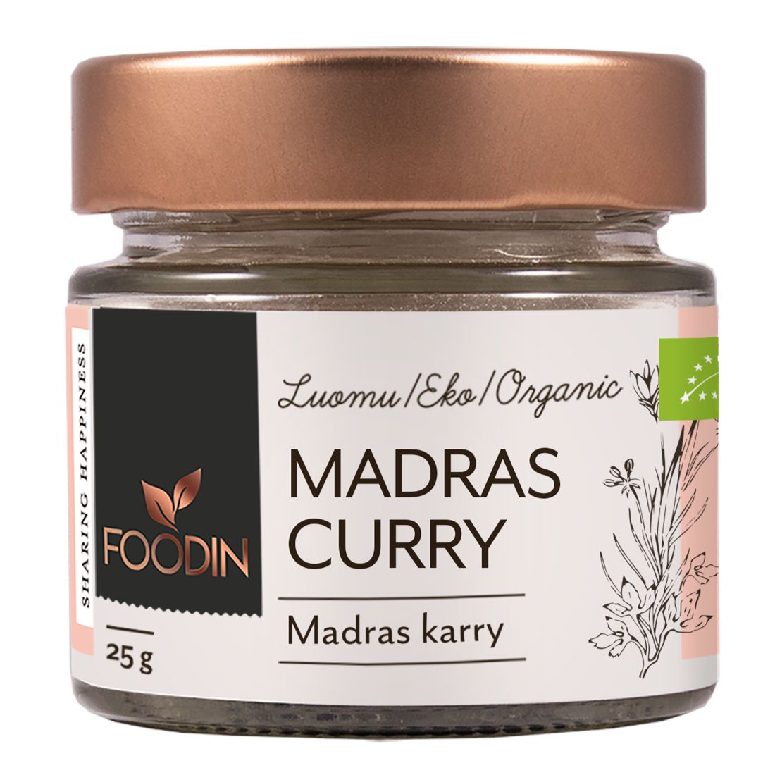 A glass jar with a capacity label of 25g contains Foodin Madras Curry powder and has a copper-colored metal lid. The label features a detailed botanical illustration, the Foodin logo, and product name in clean, modern typography; “organic” is also legible. The surface of the jar is smooth and glossy. No hands or people are present. The background is neutral and uncluttered.
