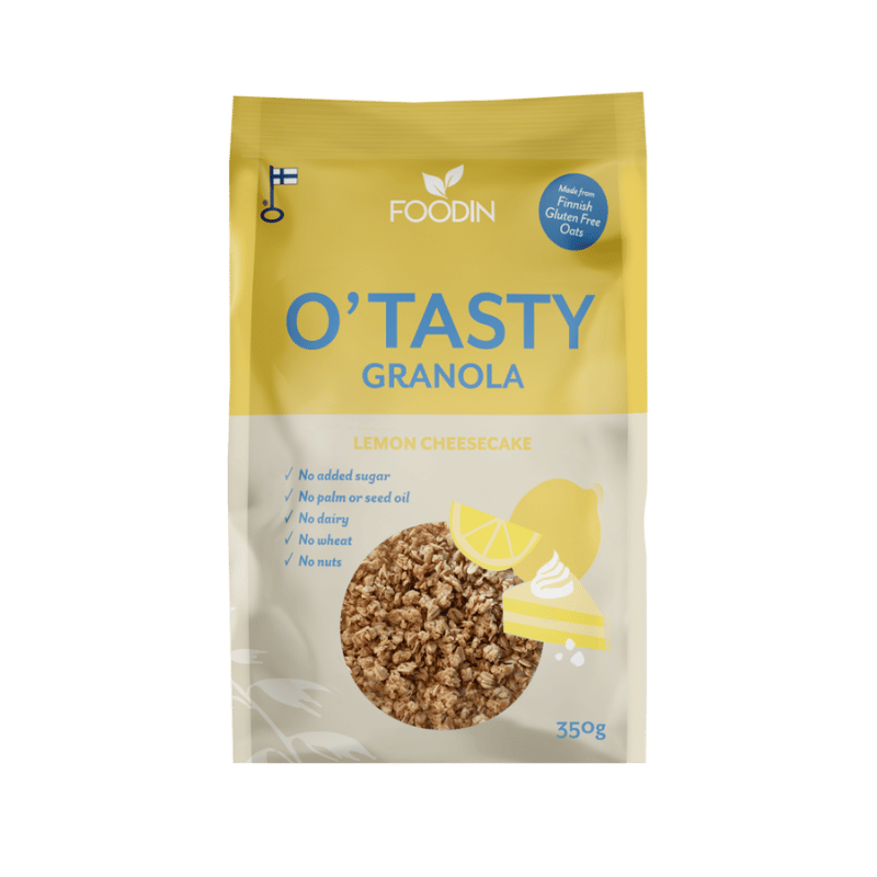 Keltainen ja valkoinen pussi Foodin OTasty Granola -mysliä, Lemon Cheesecake -makuisena, 350 g. Suorakulmainen pussi mattapinnalla. Etukuvassa on irtomysliä sitruunaviipaleiden vierellä. Suuri tuotenimi ja makumerkintä lihavoidulla pääteviivattomalla fontilla; lisätekstinä gluteeniton, ei lisättyä sokeria, pähkinätön. Siisti vaalea tausta, ei ihmisiä tai muuta rekvisiittaa näkyvissä.