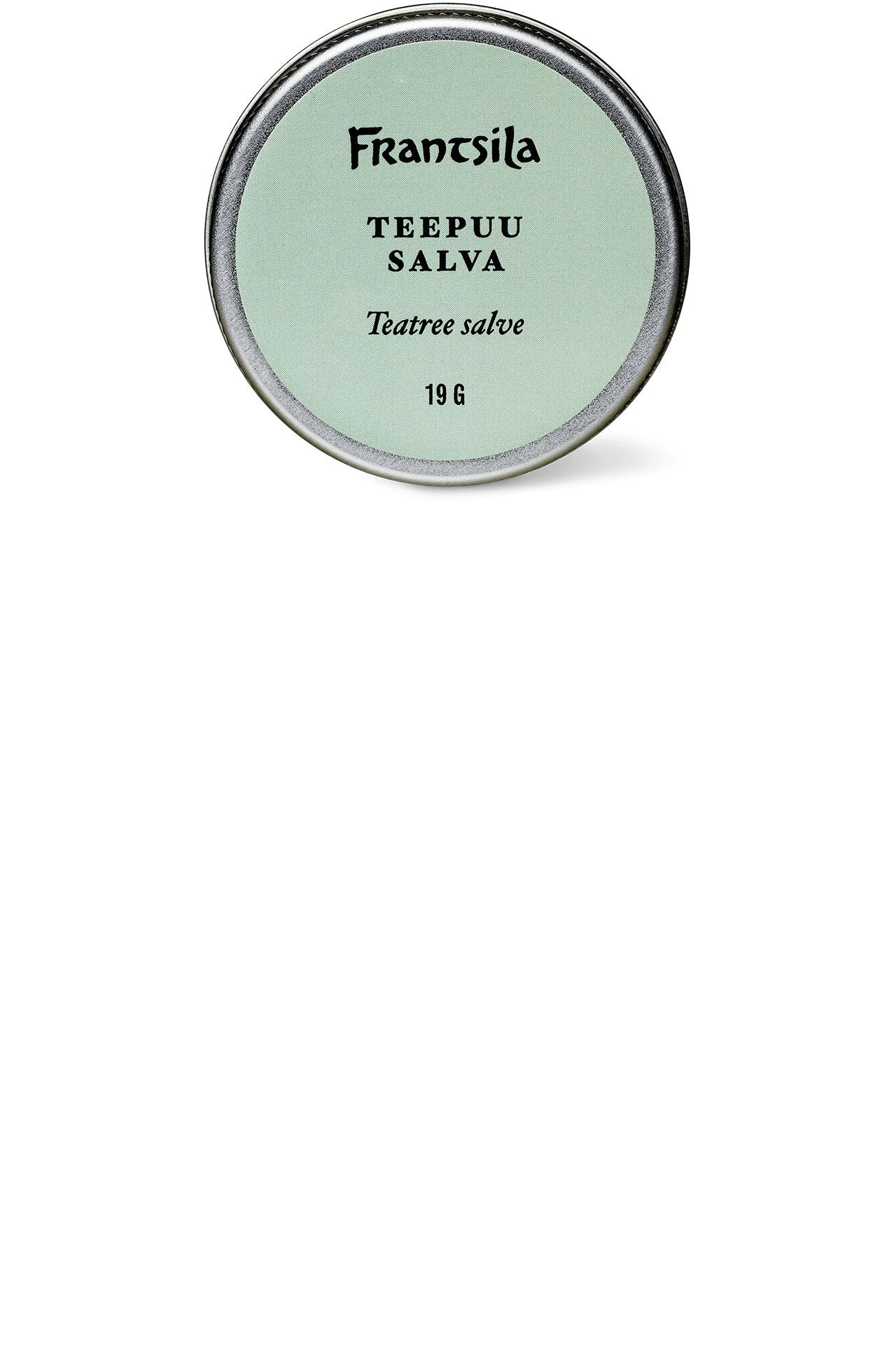 A round tin of Frantsila Teatree Salve with a light green matte label and black, sans-serif text showing the product name and 19 grams weight. The tin has a metal finish. No people or hands are visible. Background is plain white. Photo shows the tin from above. A round tin of Frantsila Teatree Salve with a light green label and black text, displaying the product name and weight of 19 grams. This soothing salve is infused with natural teatree oil, ideal for daily skin care.