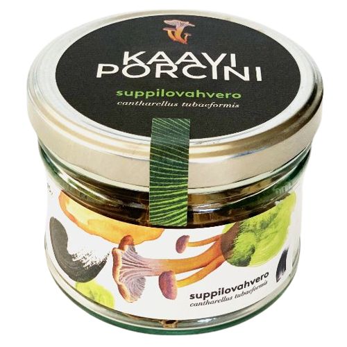 A glass jar labeled Kaavi Porcini contains dried Chanterelle mushrooms (suppilovahvero). The cylindrical clear glass shows the contents inside. The screw-top lid and white label display mushroom illustrations with green accents. Label text includes product and variety names, in a serif font. The surface is smooth and glossy. Plain light background, product centered, no people or hands visible.