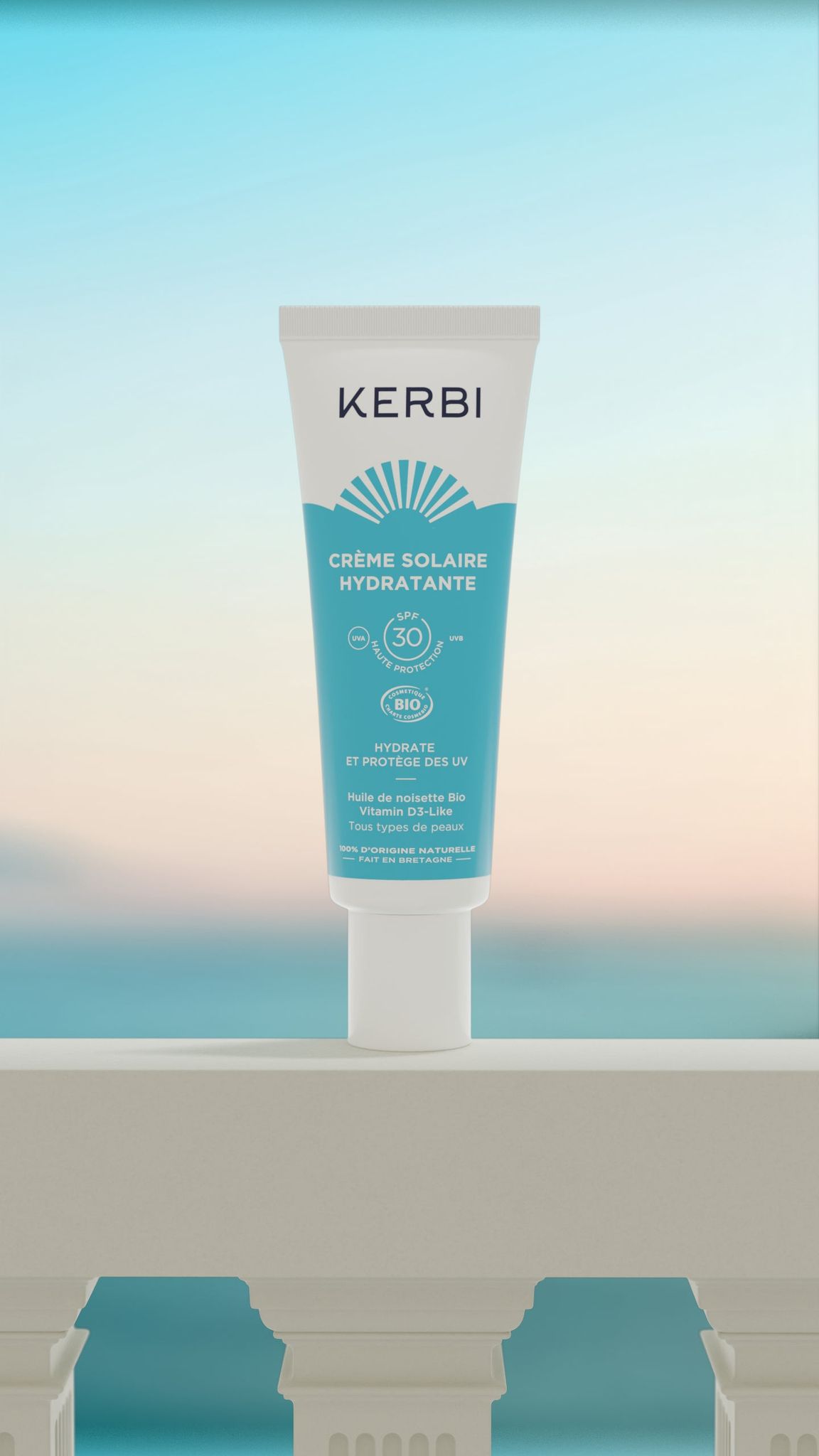 Kerbi Kosteuttava Kasvovoide SPF 30; tuubi KERBI Crème Solaire Hydratante SPF 30 -aurinkovoidetta seisoo pystyssä valkoisella kaidepinnalla, taustalla sumea meri ja pastellinvärinen taivas; tuubi lieriömäinen, pystyssä, muovia mattapinnalla; etikettitekstissä tuotenimi ja SPF-taso selkeällä groteskilla; ei ihmisiä tai käsiä näkyvissä; tuotekuva ulkoilmamaisemaa vasten.