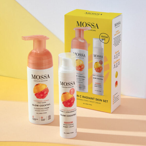 Mossa Vitamin C Lahjasetti; Glow Cocktail -ihonhoitosetti, jossa puhdistusvaahto, yövoide ja värikäs pakkaus pastellinkeltaisella ja pinkillä taustalla; tuotteissa on sylinterinmuotoisia tuubeja ja purkkeja kiiltävin valkoisin korkein ja monivärisin etiketein; pakkausten värit sisältävät oranssia, pinkkiä, keltaista ja violettia; typografia on lihavoitua groteskia; kuva on tasokuva ylhäältä, ei ihmisiä tai käsiä näkyvissä.