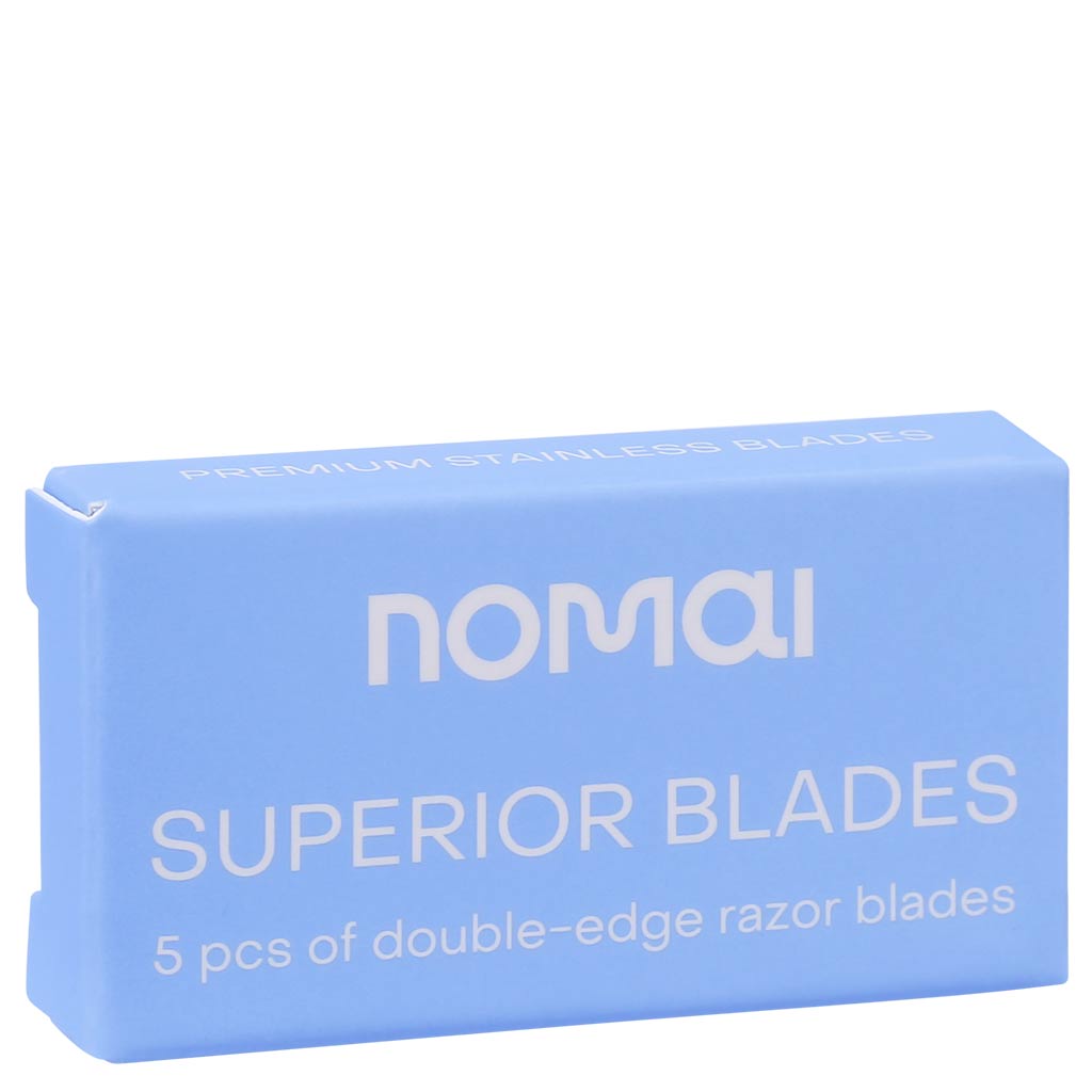 Nomai Superior Blades; sininen pakkaus tekstillä nomai SUPERIOR BLADES, sisältää 5 laadukasta ruostumattomasta teräksestä valmistettua partaterää; suorakaiteen muotoinen pakkaus tasaisella mattapinnalla ja terävin reunoin; lihavoitu valkoinen groteskiteksti, SUPERIOR BLADES isoin kirjaimin; terät osittain näkyvissä pienen ikkunan läpi pakkauksen etuosassa; vaalea tausta, ei ihmisiä tai käsiä; tavanomainen keskitetty tuotekuva.