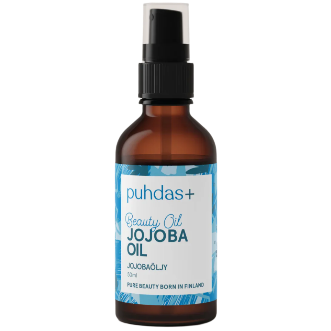 Puhdas+ Beauty Oil Jojobaöljy -pullo, 50 ml; ruskea lasipullo mustalla muovisella pumppukorkilla, pystyssä yksiväristä taustaa vasten; etiketissä sinisiä ja valkoisia lohkoja selkeällä tekstausvapaalla kirjasimella, teksti "Pure beauty born in Finland"; pullon pinta kiiltävä; ei ihmisiä tai käsiä näkyvissä.