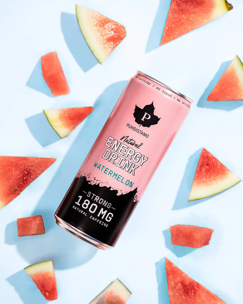 Puhdistamo Natural Energy Drink Watermelon Strong; vaaleanpunainen lieriömäinen tölkki tekstillä ”Puhdistamo Natural Energy Drink Watermelon flavor” pystyasennossa tasaisella sinisellä taustalla; tölkki mattapintainen, moderni musta-valkoinen groteskityyppografia; tölkin ympärillä tuoreita vesimelonipaloja, joissa näkyvissä punaista hedelmälihaa ja vihreää kuorta; ei ihmisiä tai käsiä kuvassa.