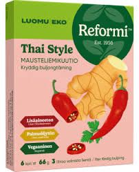 Reformi Luomu Thai Style Mausteliemikuutio: suorakulmainen pakkaus mattapinnalla, etiketissä kuvat inkivääristä ja punaisesta chilistä; etiketti on jaettu vihreään ja pinkkiin osaan, selkeä palkkiteksti suomeksi ja ruotsiksi; tausta on yksinkertainen, ei ihmisiä tai käsiä näkyvissä.
