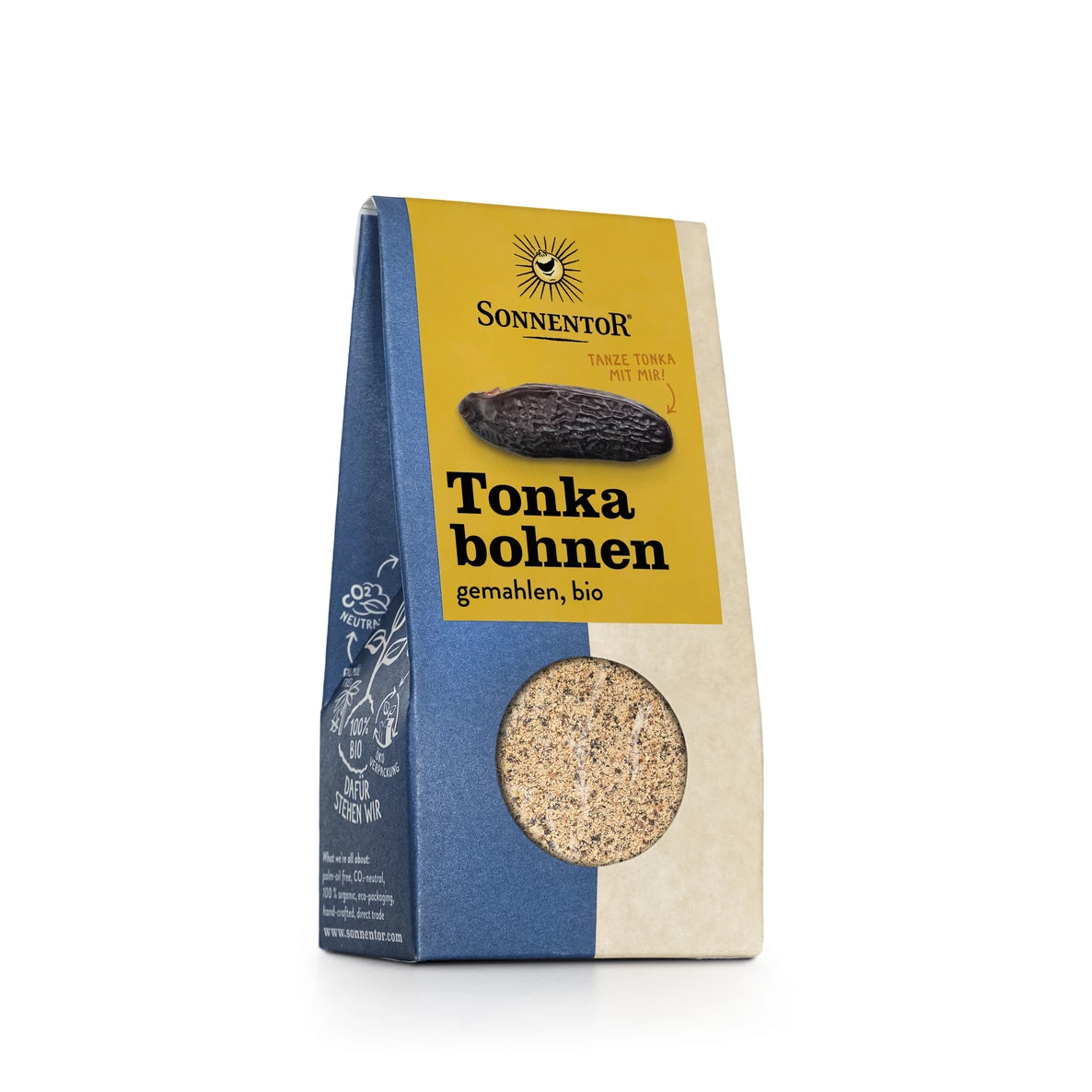 Pakkaus Sonnentorin jauhettuja luomutonkapapuja, keltaisella ja sinisellä etiketillä, jossa on tonkapavun kuva ja kirkas ikkuna paljastamassa tuoksuvan mausteen sisällä. Laatikko on suorakulmainen, valmistettu mattapintaisesta pahvista. Etikettiteksti on painettu pääteviivattomalla fontilla. Tuote seisoo valkoisella taustalla edestä kuvattuna. Ihmisiä tai käsiä ei näy.