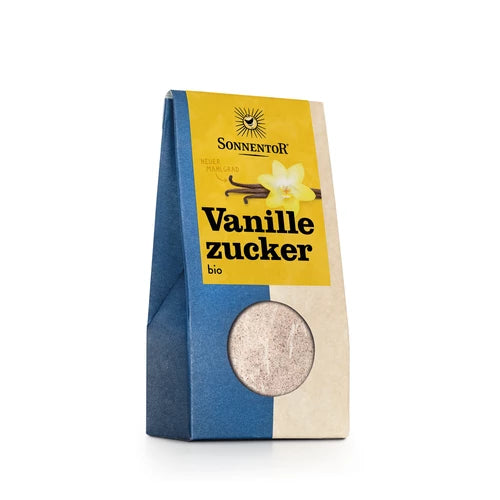 Sininen ja beige Sonnentor-luomuvaniljasokeripakkaus, merkitty Vanillezucker bio, jossa on ikkuna näyttämässä sokeri sekä keltainen etiketti eloisalla vaniljankukkakuvalla. Pakkaus on suorakulmainen mattapinnalla. Etikettien typografia on lihavoitu ja selkeä. Ihmisiä tai käsiä ei näy. Tuote on esillä pelkistetyllä taustalla suoraviivaisessa studiokuvassa.
