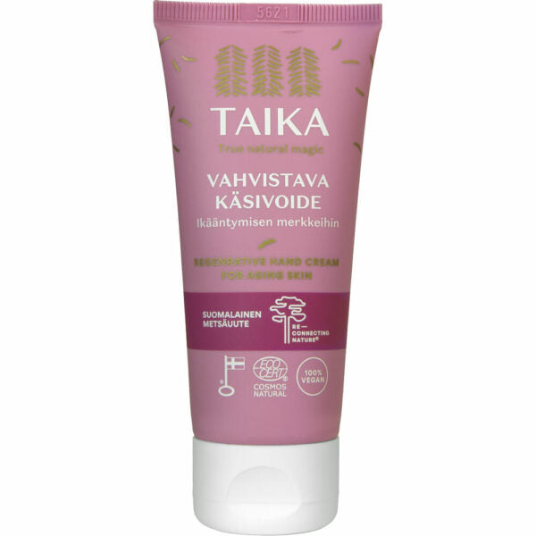 Vaaleanpunainen Taika-käsivoideputkilo, merkitty Vahvistava Käsivoide for aging skin, pehmeää mattamuovia kierrekorkilla; etiketissä kuvakkeita vegaanisuudesta, eläinkokeettomuudesta, ei mikromuoveja ja Cosmos Natural -sertifikaatista; typografia valkoista ja groteskia; tausta valkoinen; ei ihmisiä tai käsiä näkyvissä kuvassa.
