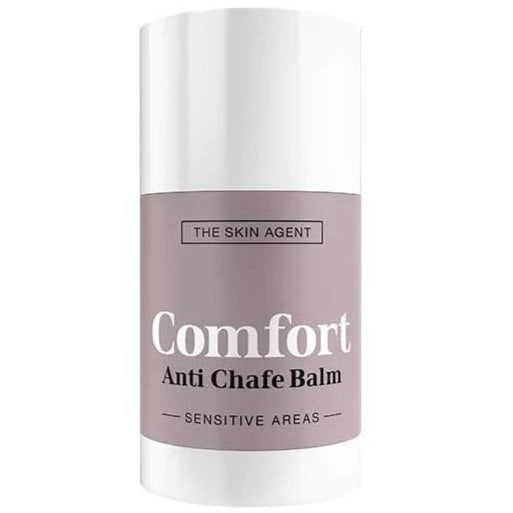 The Skin Agent Comfort Anti Chafe Balm; puikko The Skin Agentin Comfort Anti Chafe Balm -tuotetta, suunniteltu herkille alueille; muovinen sylinterinmuotoinen säiliö on mattavalkoinen alaosan beigellä etiketillä; etiketissä selkeää, suuraakkosista valkoista groteskitekstiä; ei näkyviä ihmisiä tai käsiä; yksivärinen tausta tasaisessa valaistuksessa; studiotuotekuva, keskitetty sommittelu.