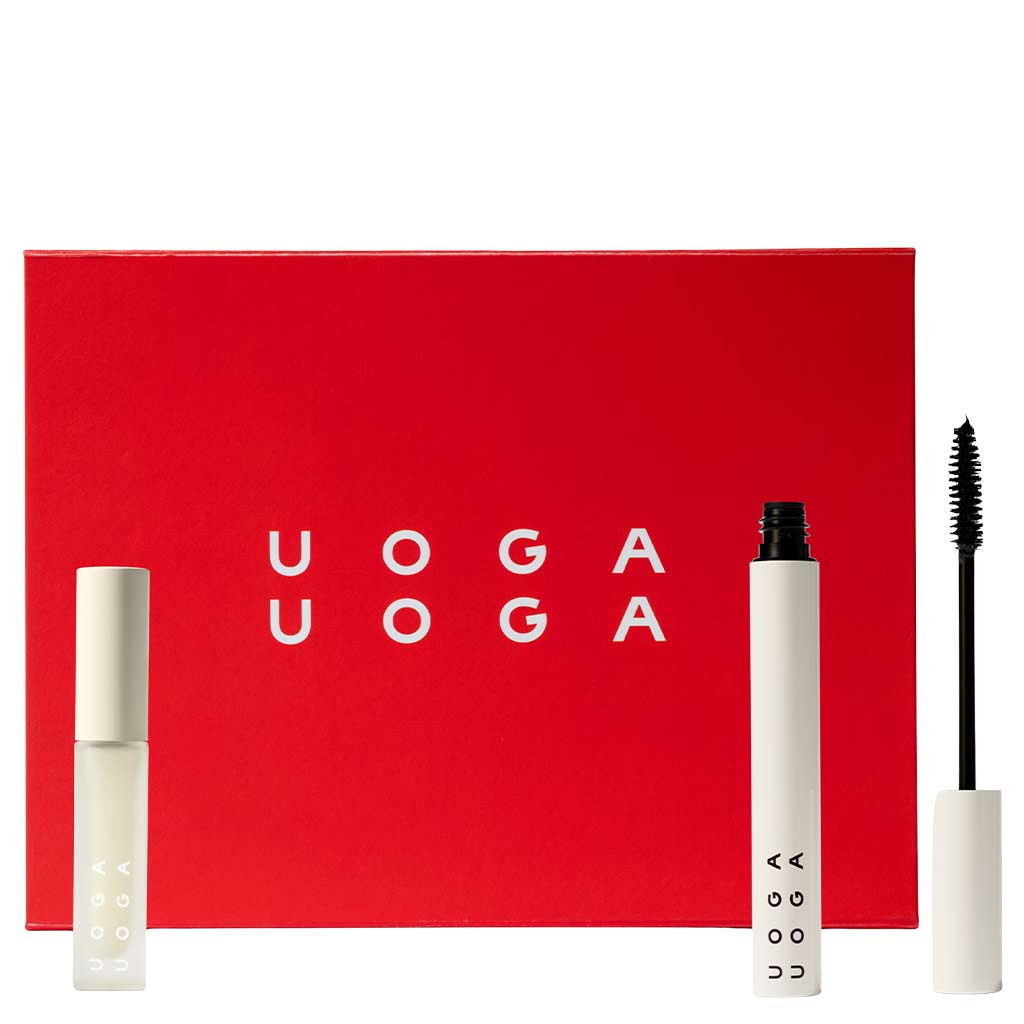 Uoga Uoga Gift Set No. 2; kirkkaanpunainen suorakaiteen muotoinen laatikko tekstillä Uoga Uoga valkoisin kaunokirjoituskirjaimin, mattavalkoinen lieriömäinen ripsivärituubi avattuna näyttäen suoran mustan harjan, sekä suljettu mattavalkoinen lieriömäinen huulikiiltopullo, kaikki aseteltuna laatikon eteen neutraalia taustaa vasten; ei ihmisiä tai käsiä kuvassa.