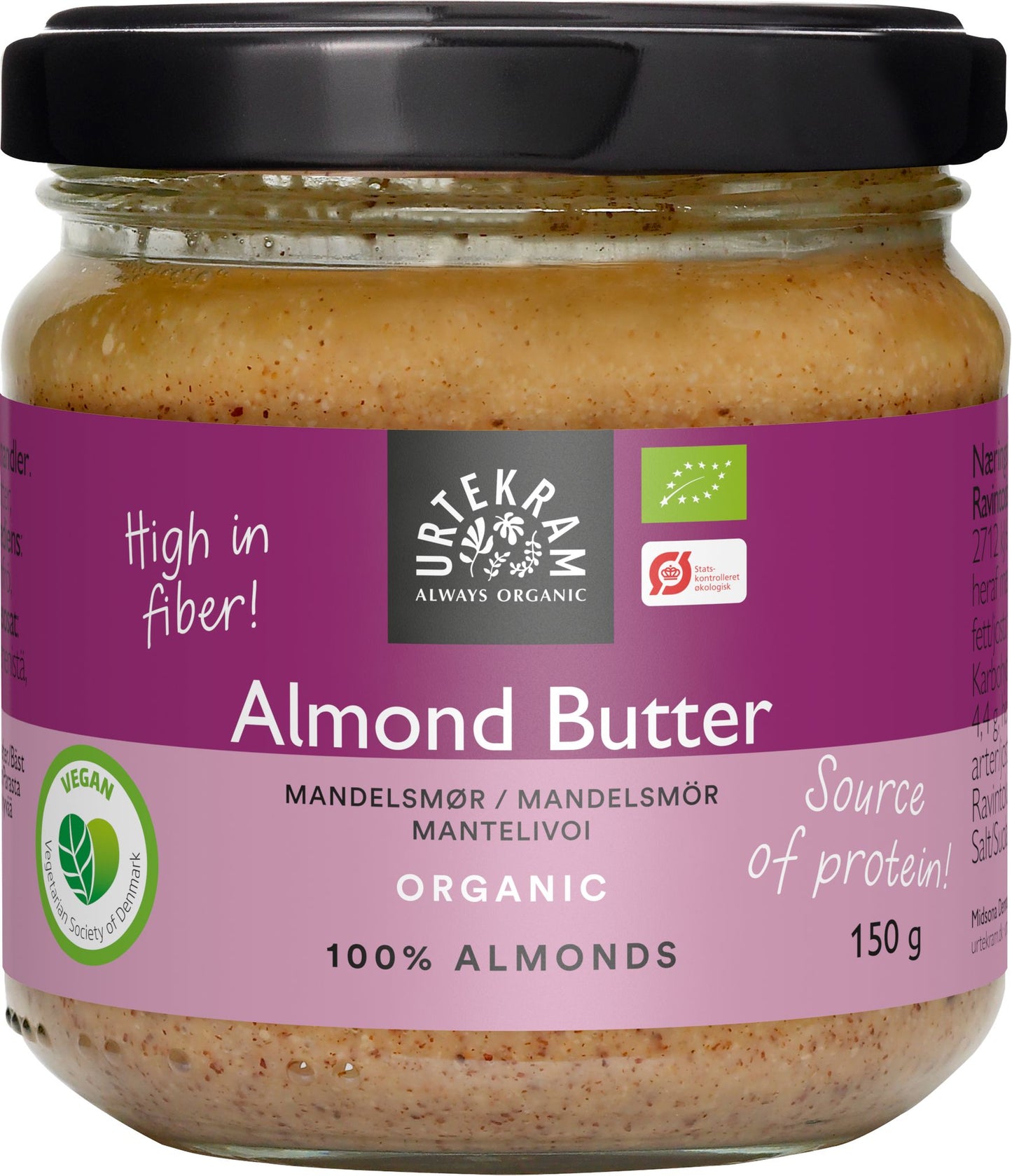 A jar of Urtekram organic almond butter with labels highlighting high in fiber, source of protein, 100% almonds, vegan, and 150g. The container is cylindrical with a metal lid and has purple and clear areas on the label that allow visibility of the almond butter. Label type features simple sans-serif fonts. The background is plain white with soft shadows. No people or actions are present.