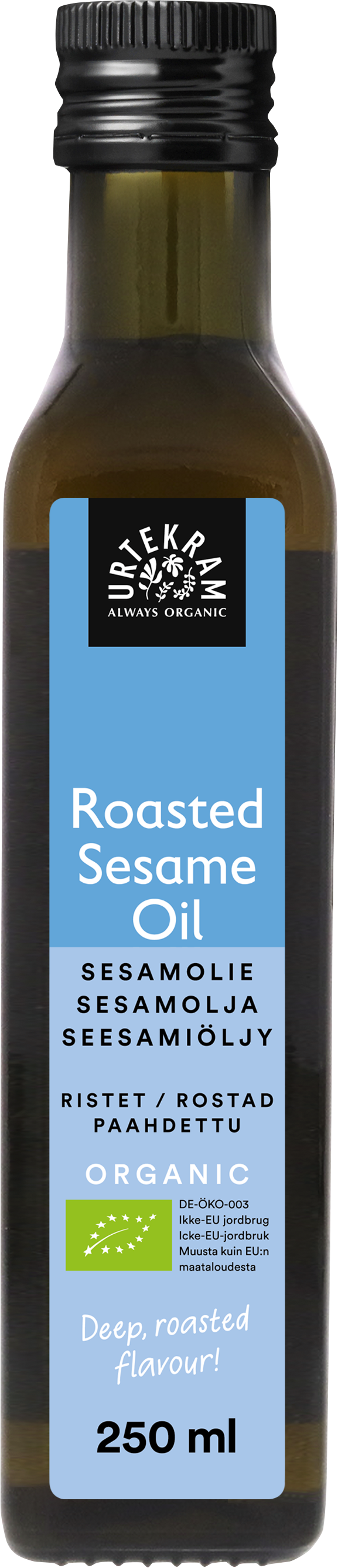 Urtekram Luomu Paahdettu Seesamiöljy, pullo luomupaahdetulle seesamiöljylle sinisellä etiketillä, tuotenimi näkyy usealla kielellä ja tilavuus 250 ml, korostaen premium-laatua; pullo sylinterimäinen, tummaa lasia mattapinnalla ja kierrekorkilla; sinisessä etiketissä valkoista groteskitekstiä ja vähäisiä graafisia elementtejä; tausta valkoinen, ei ihmisiä eikä käsiä näkyvissä; suoraan edestä otettu tuotekuva.