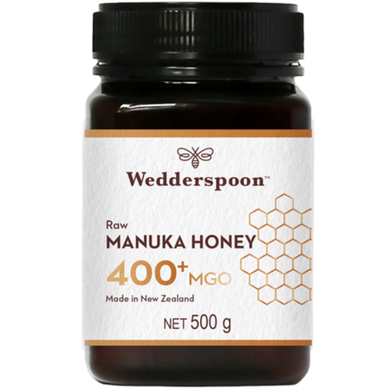 Wedderspoon Manuka-hunaja 400+ MGO; purkki Wedderspoon Raw Manuka Honey 400+ MGO, 500 g, valkoinen etiketti hunajakennokuvioin, musta muovinen kierrekansi, lieriömäinen muoto ja kiiltäväpinta; etiketissä lihavoitua groteski- ja pienempää serif-tekstiä, jossa mainitaan New Zealand ja authentic Manuka honey; tuote kuvattu vaalealla taustalla ilman ihmisiä tai rekvisiittaa.