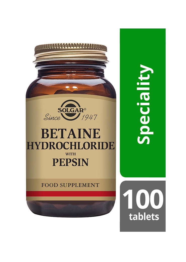 Ruskea pullo merkinnällä SOLGAR Betaine Hydrochloride with Pepsin Food Supplement seisoo pystyssä vihreän Speciality-bannerin ja valkoisen suorakulmaisen 100 tablets -laatikon vieressä. Pullo on lieriömäinen kultaisella korkilla, valmistettu lasista mattapinnalla, ja siinä on lihavoitua antiikvatekstiä. Ihmisiä tai käsiä ei näy. Tausta on pelkistetty ja hyvin valaistu.
