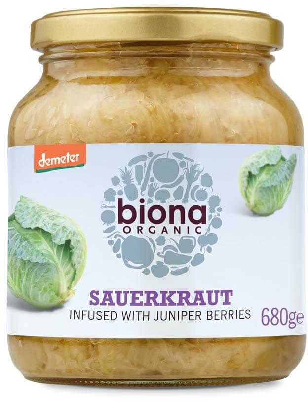 Biona Organic Hapankaali, luonnollisesti käytetty ja maustettu katajanmarjoilla; lieriömäinen, kirkas lasipurkki kultaisella metallisella kierrekannella; etiketti mattapaperia, kaalikuvituksia ja mustaa groteskitekstiä eri kokoina vaalealla pohjalla; luettavissa tuotenimi, ainesosat ja paino 680 grammaa; vaalea studiotausta, ei ihmisiä tai käsiä.