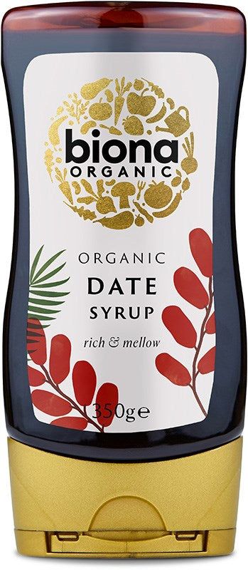 A bottle of Biona Organic Date Syrup with a gold cap, featuring a white label decorated with red leaves and a gold circular design. The plastic bottle has a dark brown, nearly black syrup inside. The label reads Organic Date Syrup, rich & mellow, 350g in sans-serif type. Product is upright on a plain white background; no people or props visible.