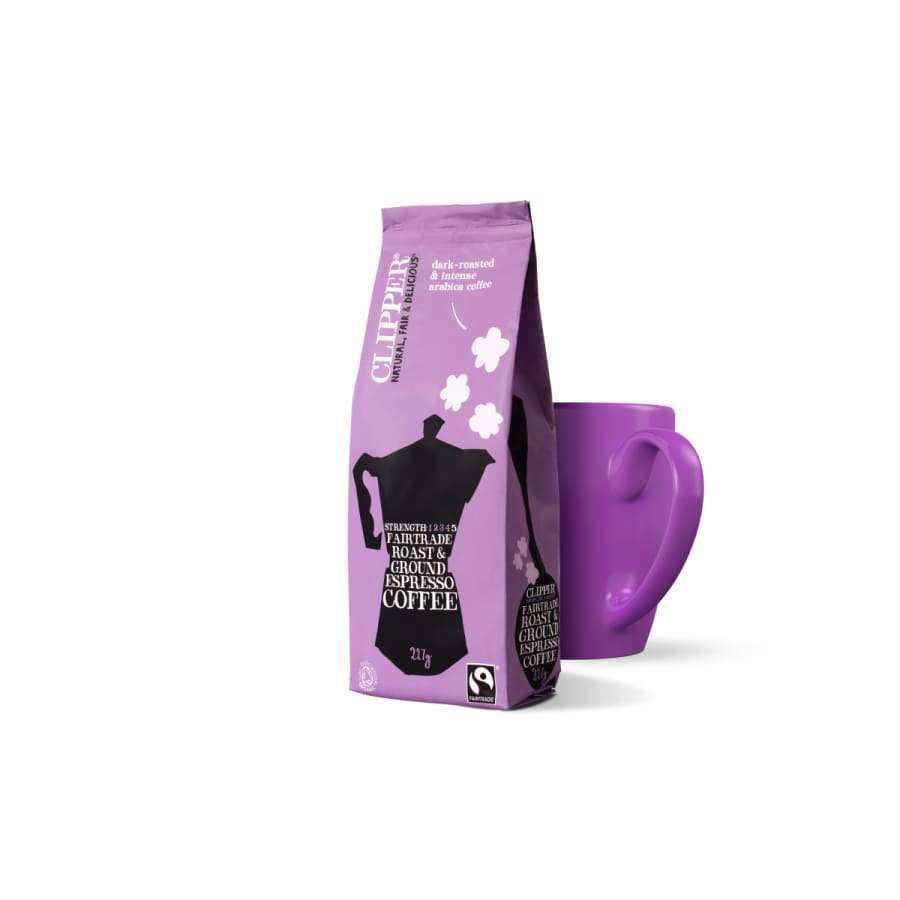 Clipper Fairtrade Espresso Coffee; violetti pussi vastaavan violetin mukin vieressä valkoisella taustalla, korostaen Fairtrade-periaatteita; pussi suorakulmainen, mattapintainen, lihavoitua valkoista tekstiä sekä brändinimi "Clipper"; muki lieriömäinen ja koristelematon; ei ihmisiä tai käsiä kuvassa.