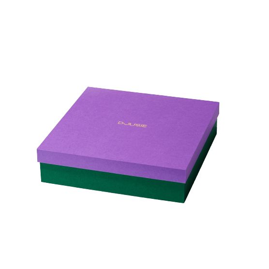 A square box with a purple lid and green base, accented by gold text in the center of the lid, set against a plain white background. The surface of the box appears matte. The typography on the lid is bold and sans-serif. There is no indication of product type or material. No people, hands, or additional packaging elements are present in the image.
