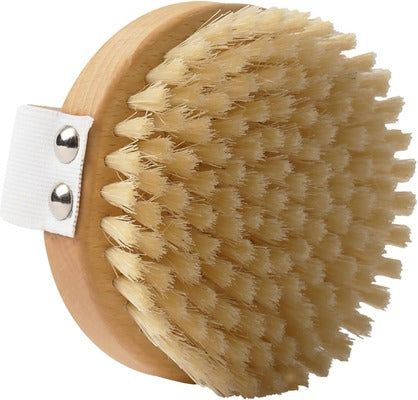 A round wooden body brush with stiff, light-colored bristles and a white cotton strap secured by two metal rivets. The wood has a matte finish. No visible logo or text on the brush. Bristles are uniformly cut and densely packed. Product is photographed alone against a plain, light background in a close-up shot. No people, hands, or packaging present.