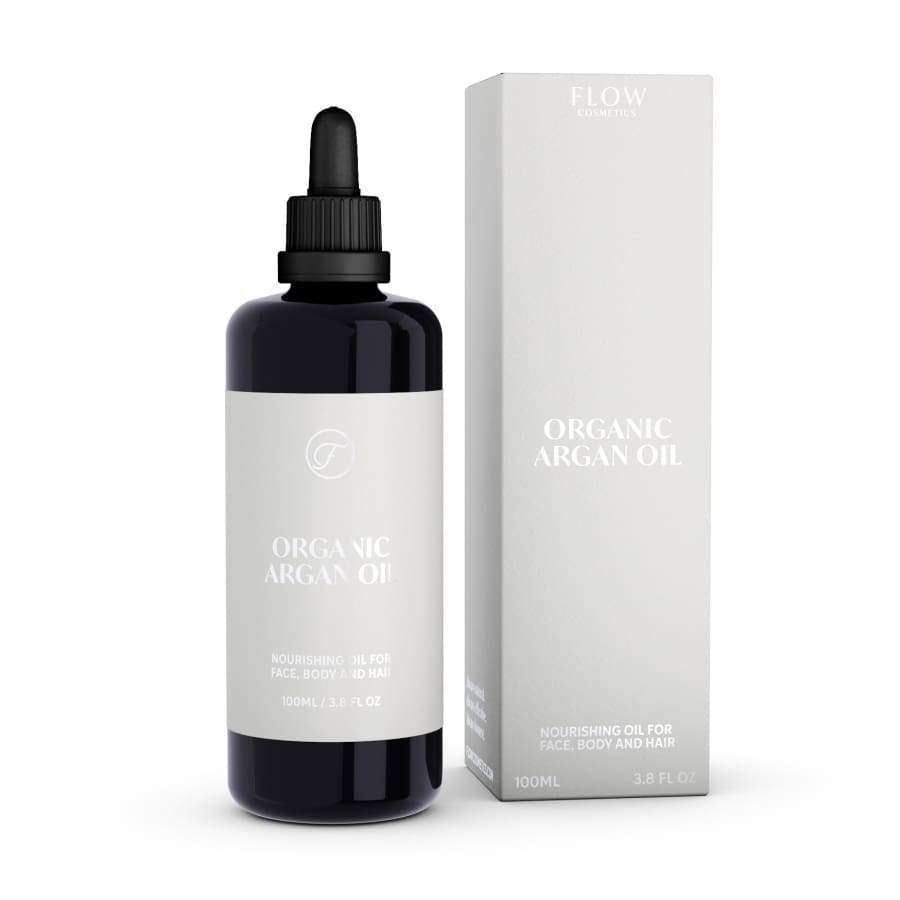 Luomu-argan-öljy tiputinpullo, 100 ml (3,3 fl oz), vastaavan rasian vieressä; molemmat valkoista, mattapintaista pakkausta yksinkertaisella mustalla groteskitekstillä; etiketissä mainitaan käyttö kasvoille, vartalolle ja hiuksille; ei ihmisiä tai käsiä; vaalea tausta, kuvattu edestä silmän tasolta.