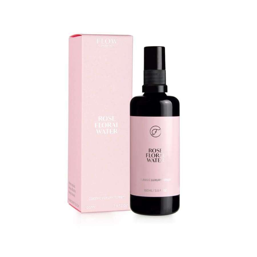 Flow Cosmetics Rose Floral Water; kirkas, lieriömäinen pullo, valkoinen suihkekorkki, teksti "Flow Cosmetics Rose Floral Water" valkoisella groteskifontilla; vieressä suorakulmainen, mattapintainen vaaleanpunainen rasia samalla tekstillä; molemmat esittävät tuotetietoja; vaalea tausta, ei ihmisiä tai käsiä; ruusuveden hento tuoksu korostuu tuotetiedoissa.