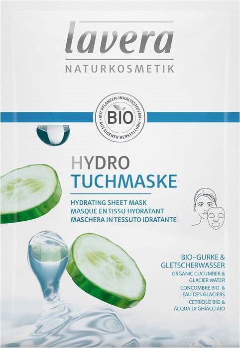 Rectangular packet with matte finish, mostly white and green color scheme. Surface shows images of cucumber slices, water splashes, and an outlined woman’s face in profile. Bold sans serif Lavera logo at top; other text in mixed font weights below. No people or hands in frame; close-up product shot against plain background. Lavera Hydro Tuchmaske packaging features images of cucumber slices, water, and an outline of a woman’s face. The text highlights this hydrating sheet mask with organic cucumber and