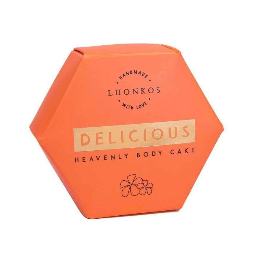 Luonkos Delicious Heavenly Body Cake, teksti "Handmade with Love"; kuusikulmainen oranssi rasia pieni kukkakuvitus alaosassa; rasia näyttää olevan kartonkia mattapinnalla; teksti selkeää ja keskitettyä kannessa groteskifontilla; ei ihmisiä tai käsiä; valkoinen tausta; tuote kuvattu ylhäältäpäin täyttäen suurimman osan kuvasta.