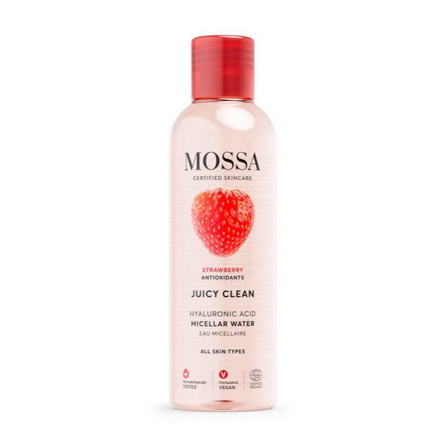A clear plastic cylindrical bottle of MOSSA Juicy Clean Micellar Water with a shiny red screw cap; the label is white with black and red sans-serif text and includes an image of a strawberry on the front. Key ingredients like hyaluronic acid and antioxidants are listed in plain type. The background is plain and light. No people or hands are present. A bottle of MOSSA Juicy Clean Micellar Water with a red cap and a strawberry image on the front, formulated with hyaluronic acid, antioxidants, and suitable