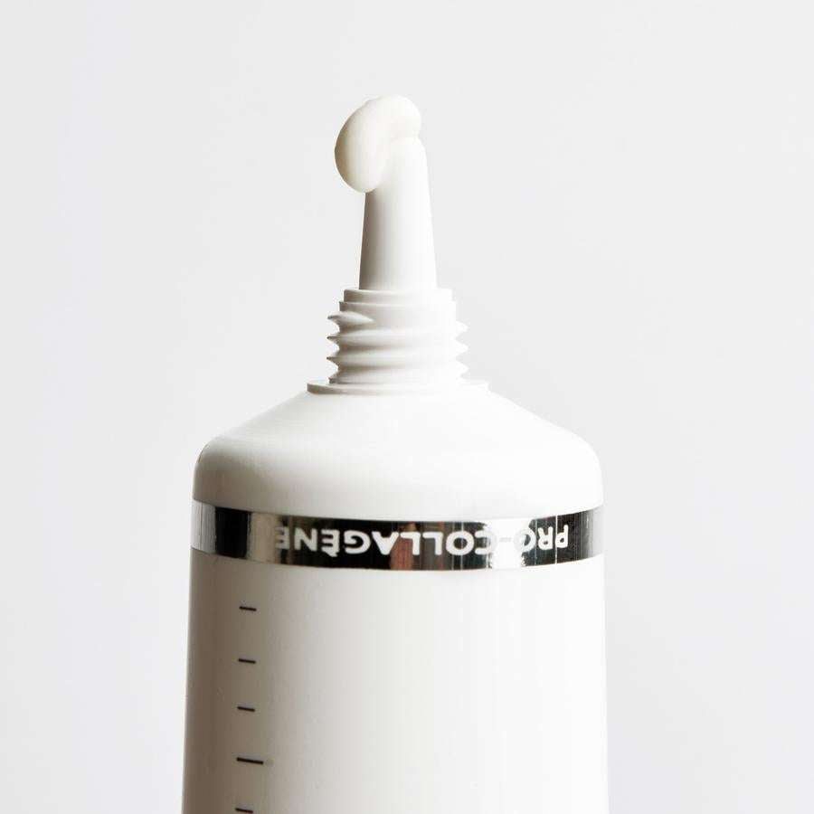 Novexpert PRO-COLLAGEN Expert Anti-Aging Fluid; lähikuva valkoisesta tuubista, jossa osittain näkyvissä teksti "PROCOLLAGEN"; suuttimesta tulee pieni määrä hoitovoidetta valkoiselle taustalle; tuubi sileä ja kiiltäväpintainen, yksinkertainen groteskikirjasin; ei käsiä tai ihmisiä kuvassa.