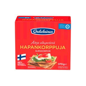 Oululainen Hapankorppuja; punainen rasia tekstillä "Oululainen HapanKorpPuJa" -näkkileipää, kuva suorakulmaisista näkkileipäviipaleista näkyvin siemenin ja lisukkein; Suomen lippu näkyvissä; mattapintainen pahvipakkaus; tuotetiedot painettu suomeksi ja ruotsiksi selkeällä groteskifontilla; rasia kuvattu yhtenäistä valkoista taustaa vasten, ei ihmisiä tai käsiä.