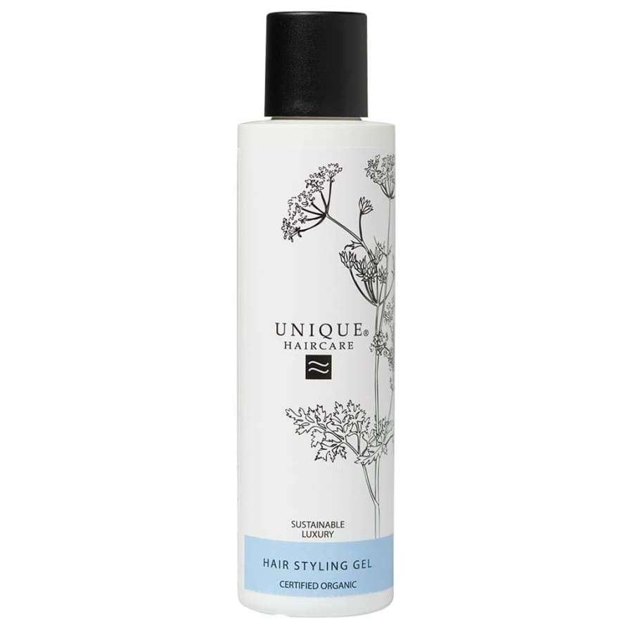 Unique Hajusteeton Muotoilugeeli; valkoinen Unique Haircare -muotoilugeelipullo kiiltävällä mustalla korkilla, kasvikuvituksia ja sininen suorakulmainen etiketti; etiketissä groteskityyppiä, luettavissa "Sustainable Luxury" ja "Certified Organic"; tausta vaalea; kuvassa vain tuote, ei ihmisiä tai käsiä.