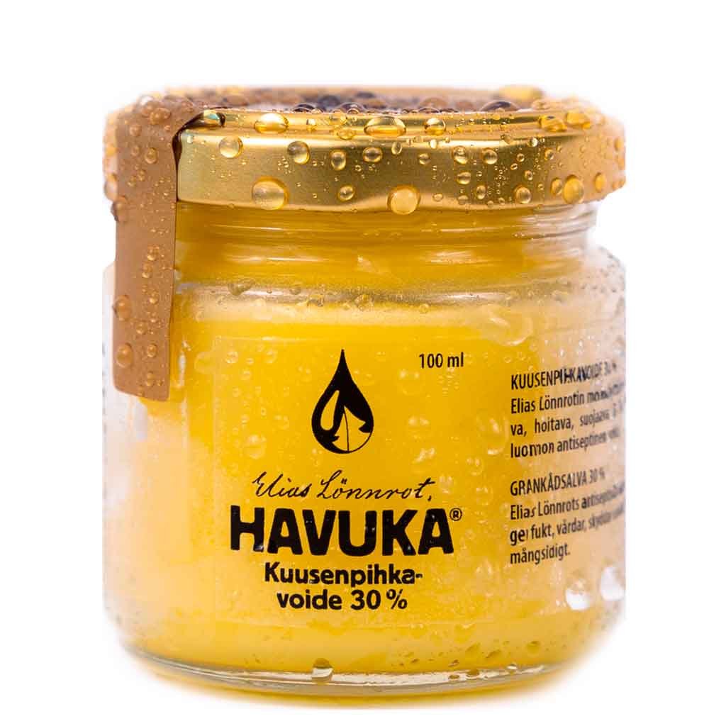 Havuka Kuusenpihkavoide 30% -lasipurkki, metallinen kultainen kierrekansi, molemmat peittyneenä näkyvin vesipisaroin; purkki sylinterimäinen ja läpinäkyvä, sisällä näkyy keltaista voidetta; etiketissä mustaa tekstausvapaata tekstiä ja puunpihkapisarasymboli; tausta yksinkertainen ja epätarkka; ei ihmisiä tai käsiä näkyvissä kuvassa.