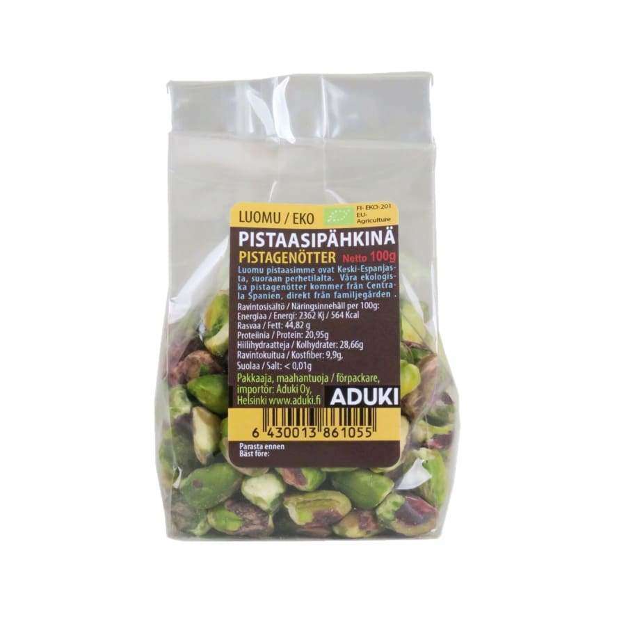 Aduki Luomu Pistaasipähkinä; kirkas muovipussi mustalla ja keltaisella suomenkielisellä etiketillä, jossa tuotetietoja ja ADUKI-brändinimi; suorakulmainen pakkaus saumattu yläreunasta; "ADUKI" lihavoidulla groteskifontilla, pienempää tekstiä alla; vaalea tausta, ei ihmisiä tai käsiä.