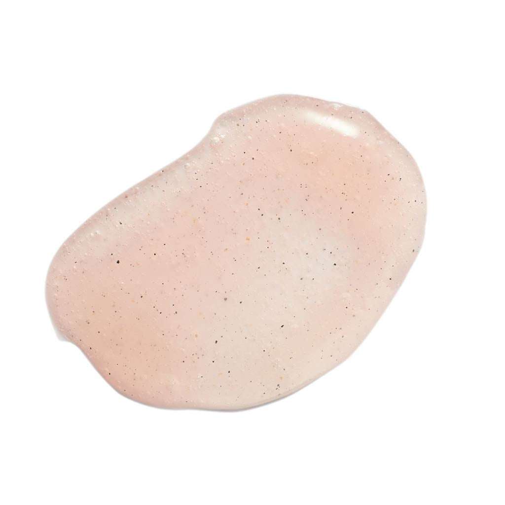 Evolve Rose Quartz Facial Polish Kasvokuorinta; lähikuva läpikuultavasta vaaleanpunaisesta geelistä pienin mustin pilkuin, levitettynä epäsäännöllisesti valkoiselle alustalle; pinta kiiltävä ja epätasainen; ei näkyvää pakkausta tai brändäystä; ei ihmisiä, etikettejä tai tekstiä kuvassa.