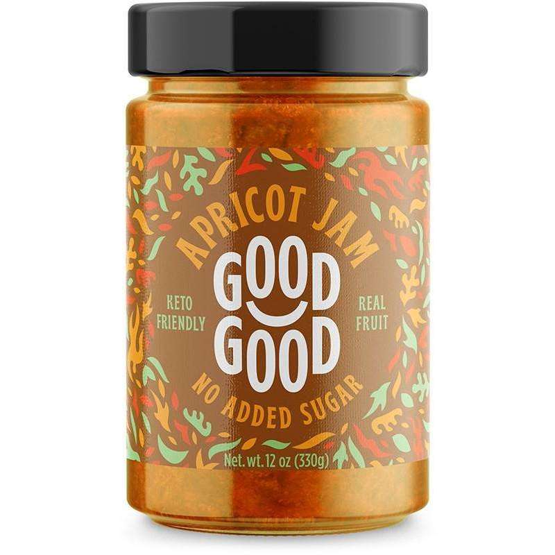 Good Good Keto Aprikoosihillo; purkki Good Good -aprikoosihilloa mustalla kannella; kirkas lasipurkki suorin sivuin ja kiiltäväpinnalla; etiketti valkoinen tyylitellyin aprikoosi- ja vihreä lehtikuvituksin; teksti lukee "No added sugar", "keto friendly", "made with real fruit", "12 oz (330g)"; groteskifontit käytössä koko tekstissä; kuvassa yksittäinen suljettu purkki yhtenäistä valkoista taustaa vasten, ei ihmisiä tai rekvisiittaa.